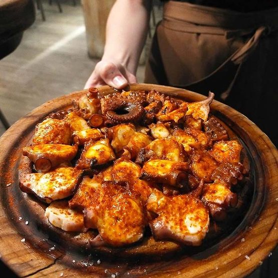 La Pulpería de Victoria persona con plato con pulpo